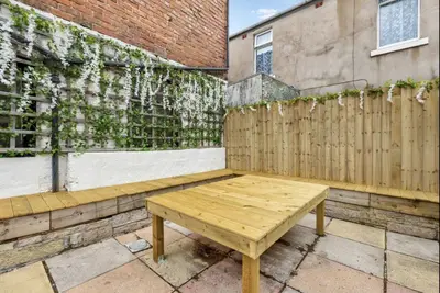 a wooden bench sitting on a patio next to a fence at Sunnyside Aparthotel Tropical suite, 10 min from Blackpool tower, outside space, free parking in Blackpool