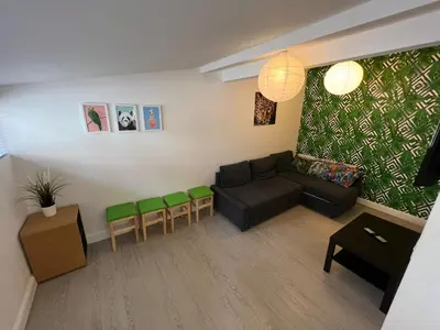 a living room with a couch and green chairs at Sunnyside Aparthotel Tropical suite, 10 min from Blackpool tower, outside space, free parking in Blackpool