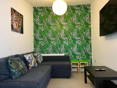 a living room with a couch and a green wall at Sunnyside Aparthotel Tropical suite, 10 min from Blackpool tower, outside space, free parking in Blackpool