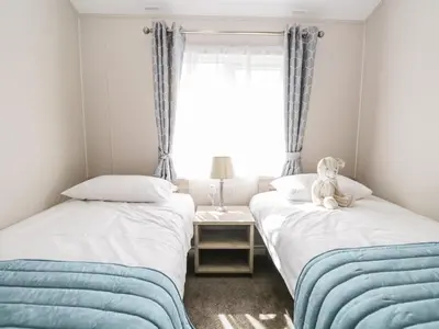 two beds in a room with a teddy bear sitting on top at Parkers Place in Carnforth