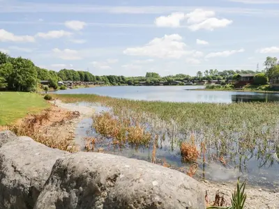 a river with a large rock in the foreground at Parkers Place in Carnforth