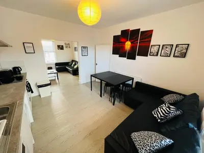 a living room with a black couch and a table at Sunnyside Aparthotel Safari suite, Free Parking, 10Min Walk To Blackpool tower in Blackpool