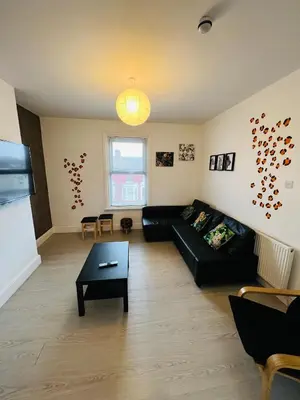 a living room with a black couch and a table at Sunnyside Aparthotel Safari suite, Free Parking, 10Min Walk To Blackpool tower in Blackpool