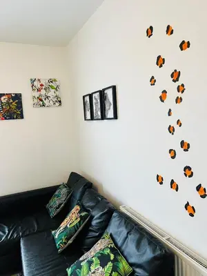 a living room with a black leather couch against a white wall at Sunnyside Aparthotel Safari suite, Free Parking, 10Min Walk To Blackpool tower in Blackpool