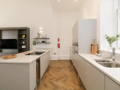 a white kitchen with white counters and a sink at Rowley House at Stone Cross Mansion in Ulverston
