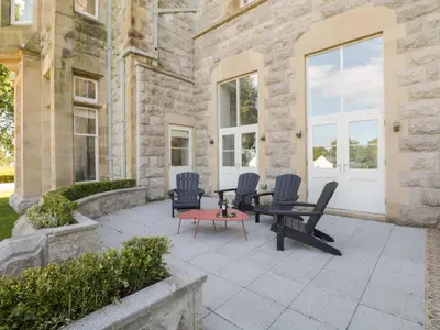 a patio with chairs and tables in front of a stone building at The Margaret Suite Stone Cross Mansion in Ulverston