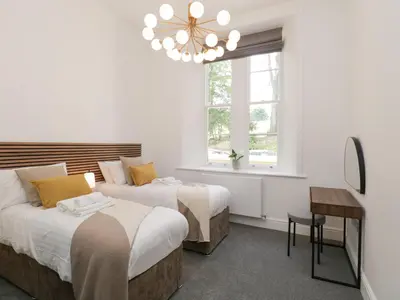 a bedroom with two beds and a chandelier at Alice House Stone Cross Mansion in Ulverston