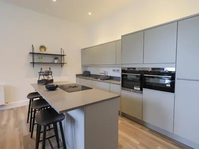 a kitchen with white cabinets and a island with bar stools at The Alfred Suite Stone Cross Mansion in Ulverston