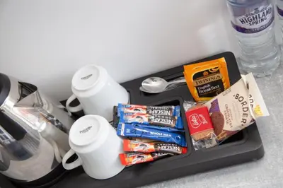 a tray with some snacks and cups on a counter at Hotel Rafay in Blackburn