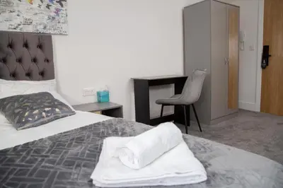 a bedroom with a bed with a desk and a chair at Hotel Rafay in Blackburn