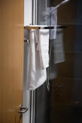 a bathroom with towels hanging on a shower door at Hotel Rafay in Blackburn