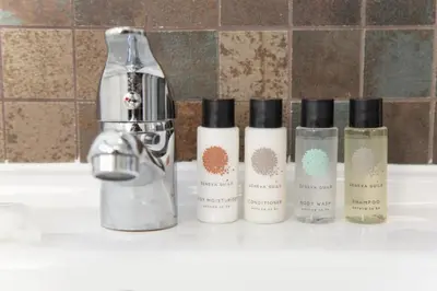 four bottles ofodorizers sitting on a bathroom sink at Hotel Rafay in Blackburn