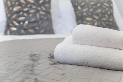 a stack of towels sitting on top of a bed at Hotel Rafay in Blackburn