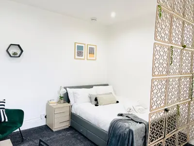 a bedroom with a bed and a green chair at Lovely Estelle Studio Apartment by CityNest in Blackpool
