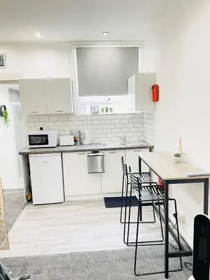 a kitchen with white cabinets and a table and chairs at Lovely Estelle Studio Apartment by CityNest in Blackpool