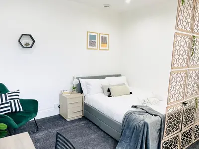 a bedroom with a bed and a green chair at Lovely Estelle Studio Apartment by CityNest in Blackpool