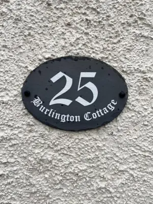 a black sign on the side of a building at Burlington Cottage - Ulverston, Lake District. in Ulverston