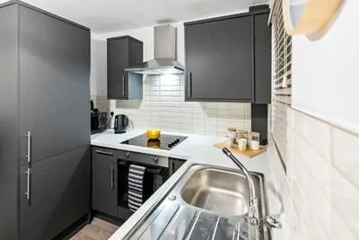 a kitchen with black cabinets and a sink at The Snug at The Hideaway STAMP SA in Blackpool