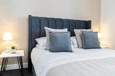 a bedroom with a large bed with blue pillows at The Snug at The Hideaway STAMP SA in Blackpool