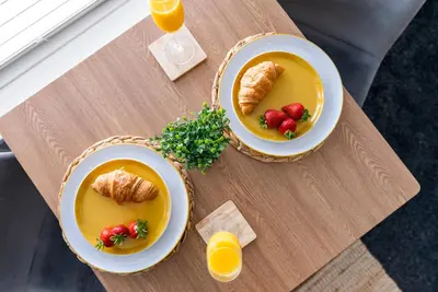 two bowls of soup with croissants and strawberries on a table at The Snug at The Hideaway STAMP SA in Blackpool
