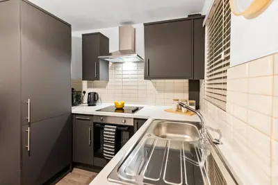a kitchen with black cabinets and a sink at The Snug at The Hideaway STAMP SA in Blackpool