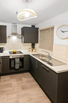 a kitchen with black cabinets and a clock on the wall at The Snug at The Hideaway STAMP SA in Blackpool