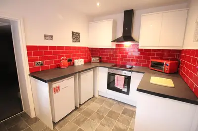a kitchen with white cabinets and red tiles at Media Manor - Fully Refurbished in 2022 - Large 6 Bedrooms, 3 Bathrooms plus Media Games Room in Blackpool