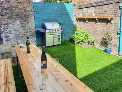 a wooden table with wine glasses and a grill at Anfield Haven in Liverpool