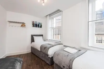two beds in a room with two windows at The Cavern Quarter Aparthotel by UStay in Liverpool
