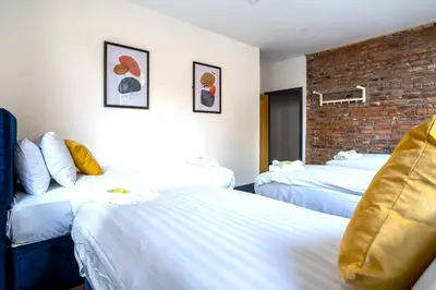 a hotel room with two beds and a brick wall at The Cavern Quarter Aparthotel by UStay in Liverpool