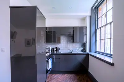 a kitchen with black and white appliances and windows at The Cavern Quarter Aparthotel by UStay in Liverpool