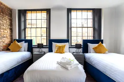 two beds in a room with two windows at The Cavern Quarter Aparthotel by UStay in Liverpool