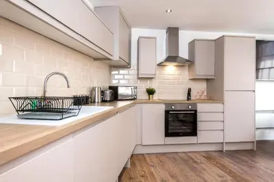a kitchen with white cabinets and a sink at The Cavern Quarter Aparthotel by UStay in Liverpool