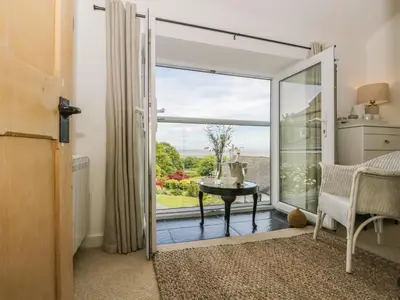 a room with a door open to a balcony with a table at Sandacre Cottage in Ulverston