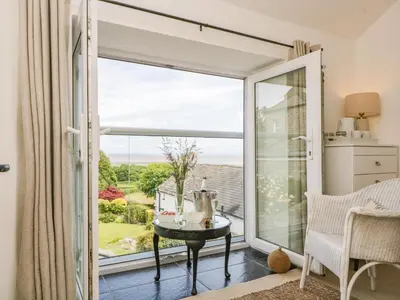 a room with a sliding glass door with a view of the garden at Sandacre Cottage in Ulverston