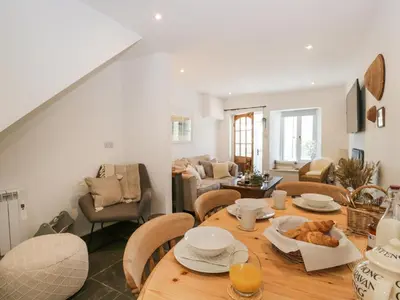 a kitchen and living room with a wooden table and chairs at Sandacre Cottage in Ulverston