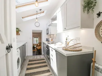 a kitchen with white cabinets and a washer and dryer at Sandacre Cottage in Ulverston
