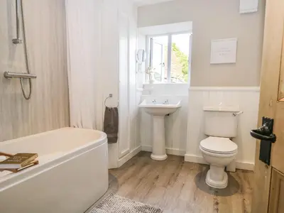 a bathroom with a tub and a toilet and a sink at Sandacre Cottage in Ulverston