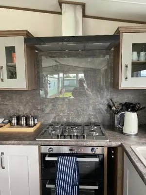 a kitchen with a stove and a person in the window at Heywoods caravan holiday home in Morecambe