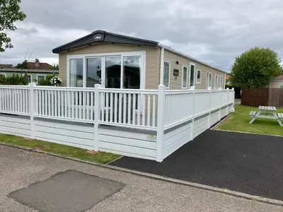 a tiny house with a white picket fence at Heywoods caravan holiday home in Morecambe