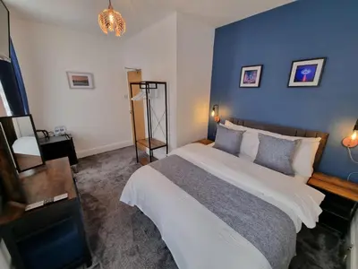 a bedroom with a large bed and a blue wall at Rendezvous Bar & Rooms - ADULTS ONLY in Blackpool
