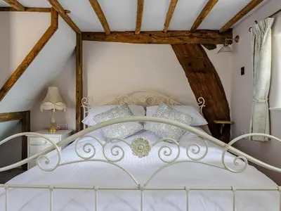 a white bed in a room with wooden beams at The Restored Cottage in Eccleston