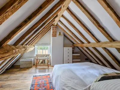 a bedroom in an attic with wooden beams at The Restored Cottage in Eccleston