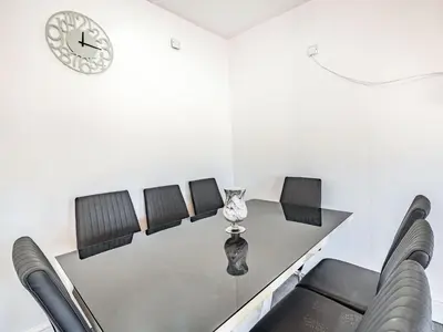 a dining room table with chairs and a clock on the wall at Sea View Apartment Two - Uk36847 in Blackpool