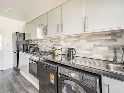 a kitchen with white cabinets and a washer and dryer at Sea View Apartment Two - Uk36847 in Blackpool