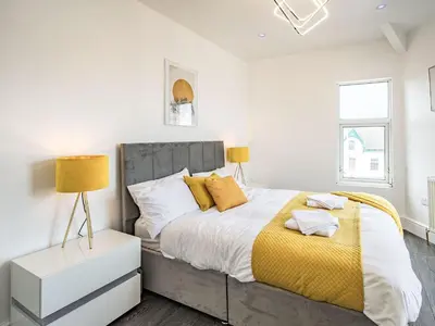 a white bedroom with a large bed with yellow pillows at Sea View Apartment Two - Uk36847 in Blackpool