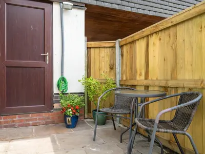 a patio with two chairs and a table and a door at The Birds Nest in Longridge