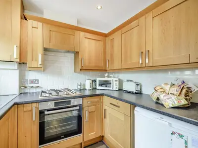 a kitchen with wooden cabinets and a stove top oven at The Birds Nest in Longridge