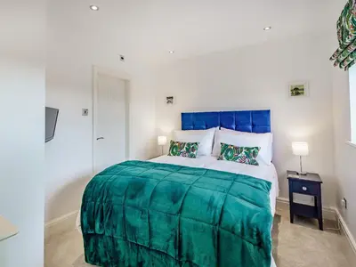 a bedroom with a large bed with a blue headboard at The Birds Nest in Longridge