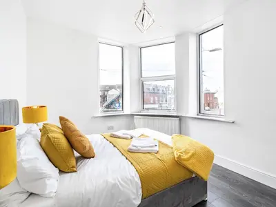 a bedroom with a bed with yellow sheets and windows at Sea View Apartment One - Uk36846 in Blackpool